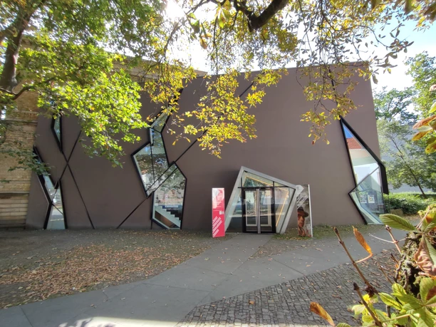 Museumsquartier Osnabrück Modernes Gebäude mit asymmetrischen Fenstern, umgeben von Herbstlaub in einer urbanen Umgebung.