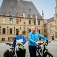 Rathaus Osnabrück mit Radfahrenden Zwei Radfahrer vor einem historischen Gebäude aus Sandstein mit deutschem und europäischem Wappen.