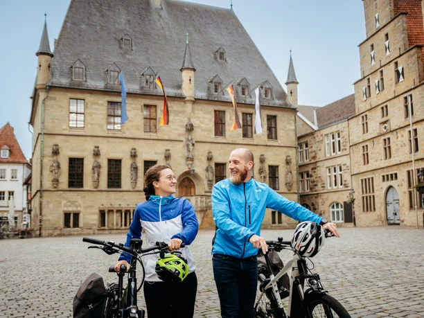 Rathaus Osnabrück mit Radfahrenden Zwei Radfahrer vor einem historischen Gebäude aus Sandstein mit deutschem und europäischem Wappen.