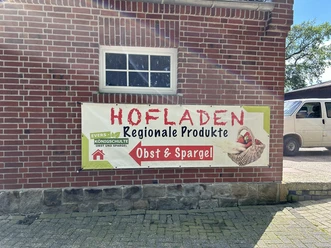 Hofladen Evers-Königschulte, Freren ©Emsland Tourismus GmbH (4).JPEG Werbeschild aus Stoff an roter Backsteinwand mit Aufschrift Hofladen Regionale Produkte Obst und Spargel