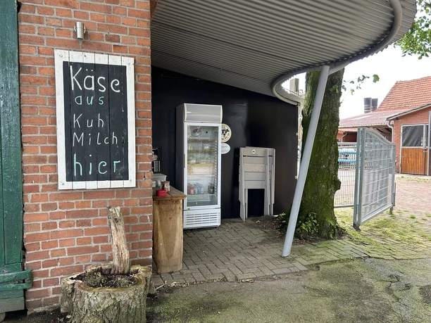 Käsehof Hüsing Freren Suttrup Verkaufsecke auf einem Bauernhof mit Kühlschrank, Holztafel und Hinweis auf Käse aus Kuhmilch