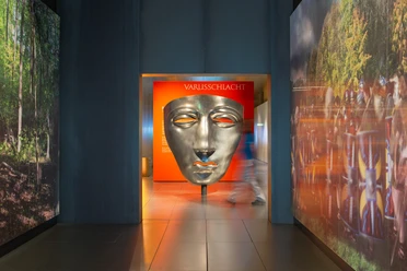 Varusschlacht im Osnabrücker Land - Museum und Park Kalkriese Große silberne Maske im Varusschlacht-Museum mit Besucher im Flur.