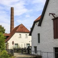 Historisches Ensemble des Tuchmachermuseums Historische Backsteingebäude mit rotem Ziegeldach und Schornstein vor blauem Himmel.Historic brick building with red tiled roof and chimney against a blue sky.Historisk murstensbygning med rødt tegltag og skorsten mod en blå himmel.Historisch bakstenen gebouw met rood pannendak en schoorsteen tegen een blauwe lucht.