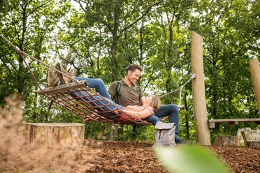 Werther-Hermannshöhen-Teutoburger-Wald-Tourismus-D-Ketz-086.jpg Ein Paar entspannt in einer Waldaussicht auf einem Netzschaukelplatz, umgeben von grünen Bäumen.