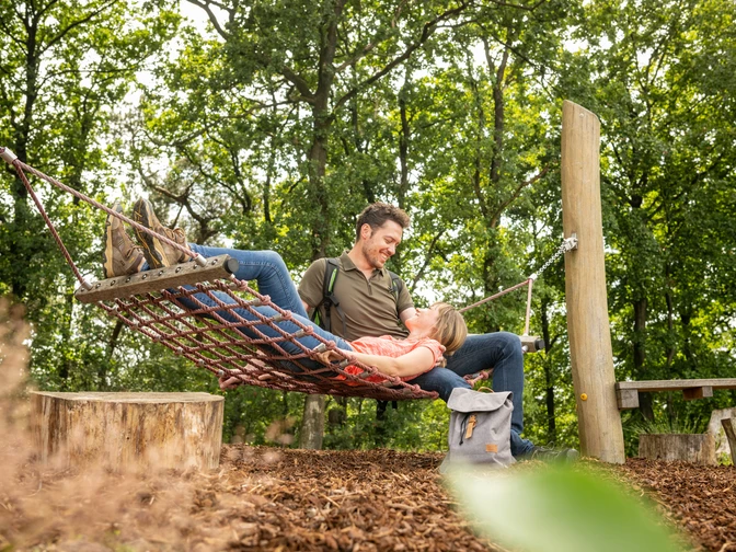 Werther-Hermannshöhen-Teutoburger-Wald-Tourismus-D-Ketz-086.jpg Ein Paar entspannt in einer Waldaussicht auf einem Netzschaukelplatz, umgeben von grünen Bäumen.