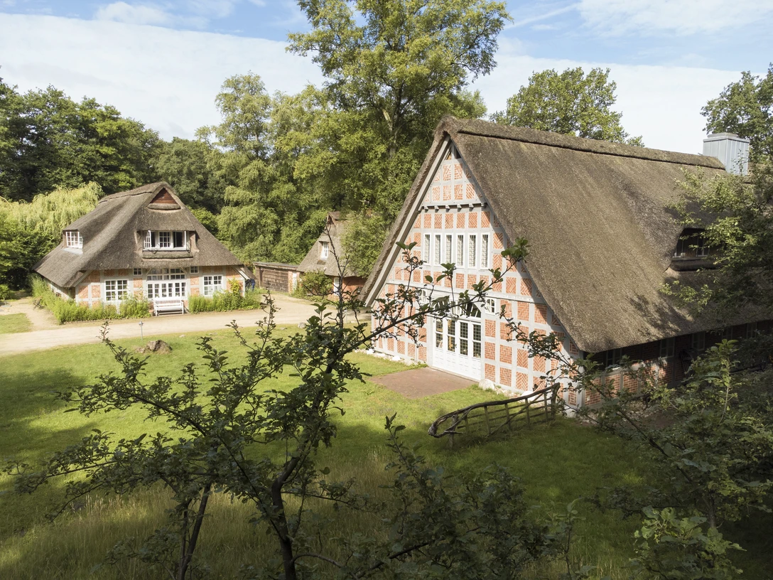 Blick auf das Haus im Schluh Blick auf das Haus im Schluh besteht aus drei roten Backsteingebäuden mit Reetdach. View of the house in the Schluh consists of three red brick buildings with thatched roofs.Udsigt til huset i Schluh består af tre røde murstensbygninger med stråtag.Zicht op het huis in de Schluh bestaat uit drie rode bakstenen gebouwen met rieten daken.