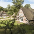 Blick auf das Haus im Schluh Blick auf das Haus im Schluh besteht aus drei roten Backsteingebäuden mit Reetdach. View of the house in the Schluh consists of three red brick buildings with thatched roofs.Udsigt til huset i Schluh består af tre røde murstensbygninger med stråtag.Zicht op het huis in de Schluh bestaat uit drie rode bakstenen gebouwen met rieten daken.