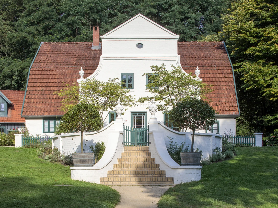 Barkenhoff Barkenhoff - ein historisches Fachwerkhaus mit einer weißen Fassade und einem roten Ziegeldach, umgeben von üppigem Grün