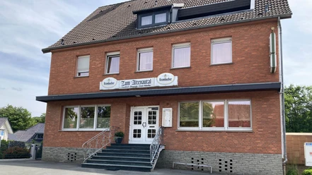 Borchen-Etteln_Gasthof-zu,-Altenautal_01 ©Kreis Paderborn.jpeg Gasthof im roten Backsteinbau mit überdachter Treppe und weißen Türen, umgeben von Bäumen.