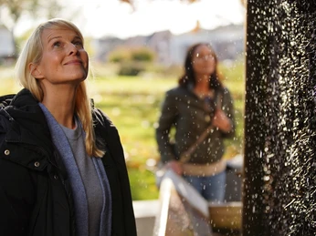 Erlebniskurpark in Bad Laer Zwei Frauen betrachten fasziniert einen glitzernden Wasserfall im Freien.Two women are fascinated by a glittering outdoor waterfall.To kvinder fascineres af et glitrende udendørs vandfald.Twee vrouwen zijn gefascineerd door een glinsterende waterval in de buitenlucht.