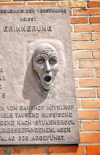 Gedenktafel am Bahnhof Hövelhof Gedenktafel am Hövelhof Bahnhof mit Relief eines schreienden Gesichts erinnert an Kriegsgefangene.