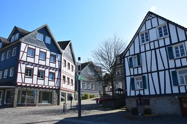 Altstadt Fachwerkhäuser in Waldbröl mit blauen Fensterläden und weiß-rot gestrichenen Fassaden im Sonnenschein.