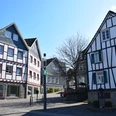 Altstadt Fachwerkhäuser in Waldbröl mit blauen Fensterläden und weiß-rot gestrichenen Fassaden im Sonnenschein.