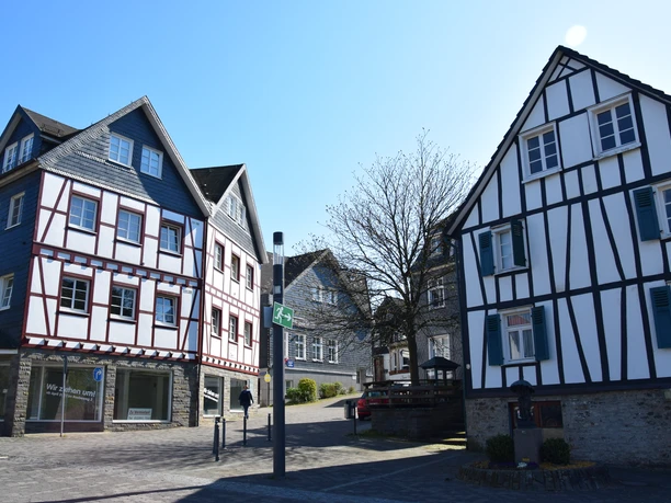 Altstadt Fachwerkhäuser in Waldbröl mit blauen Fensterläden und weiß-rot gestrichenen Fassaden im Sonnenschein.