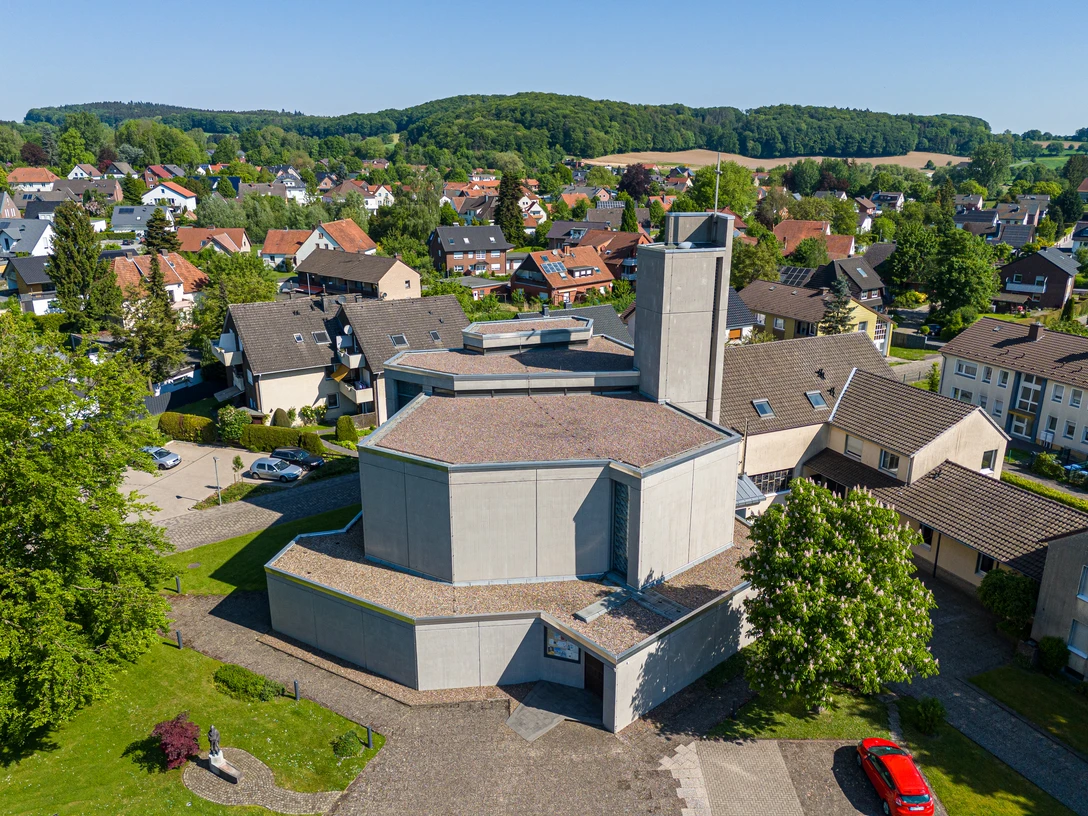 Luftaufnahme der modernen St. Bonifatius Kirche in einem grünen Wohngebiet mit umliegenden Häusern.