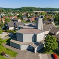 Luftaufnahme der modernen St. Bonifatius Kirche in einem grünen Wohngebiet mit umliegenden Häusern.