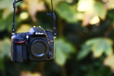 Fotografiekurs Eine Nikon D7200 Kamera hängt vor unscharfem, grünen Hintergrund.
