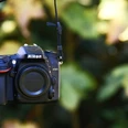 Fotografiekurs Eine Nikon D7200 Kamera hängt vor unscharfem, grünen Hintergrund.