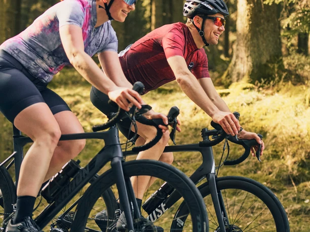 Rennrad im Sauerland Zwei Rennradfahrer auf einer sonnigen Straße durch den Wald im Sauerland