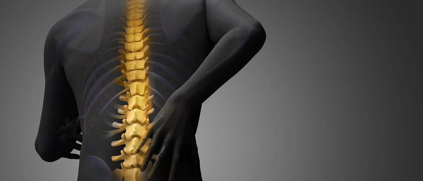 Kurs Rückenfit Mensch mit von innen leuchtender Wirbelsäule hält den schmerzenden unteren Rücken.