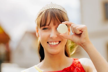 Käsekönigin Lena Schnelle mit dem Nieheimer Käse Lena Schnelle, die Käsekönigin, lächelt und hält stolz ein Stück des Nieheimer Käses vor ihr Auge.