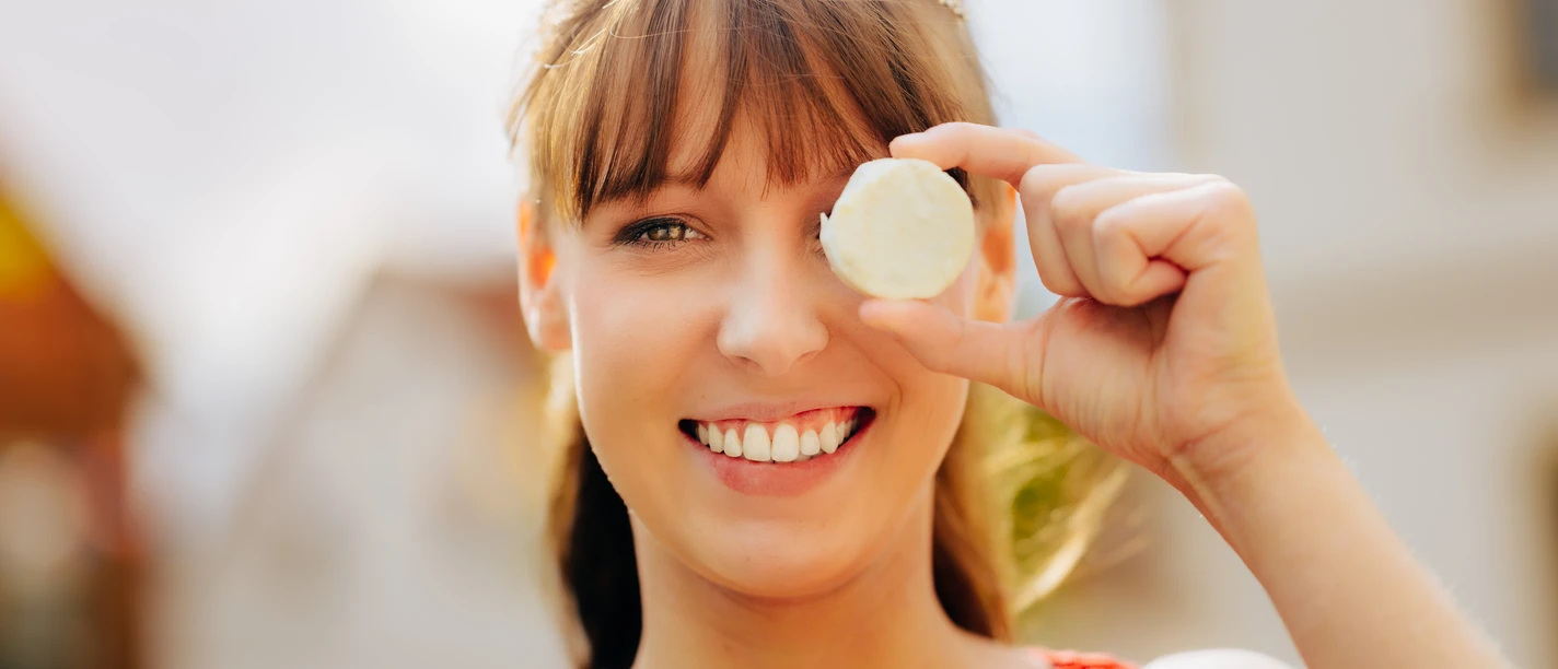 Käsekönigin Lena Schnelle mit dem Nieheimer Käse Lena Schnelle, die Käsekönigin, lächelt und hält stolz ein Stück des Nieheimer Käses vor ihr Auge.