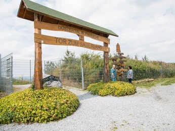 Ein hölzernes Tor mit der Aufschrift "Tor zum Sauerland" in einer ländlichen Umgebung.