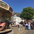 Historischer Jahrmarkt Kornelimünster Platz mit Kopfsteinpflaster, auf dem sich ein Karussell dreht.