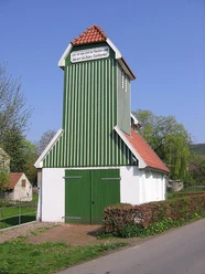 Das Feuerwehrgerätehaus Schnathorst besteht aus einem grün-weiß gestreiften Turm mit roten Dachziegeln.