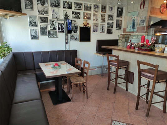 Ein einladender, heller Raum mit großen Sitzbänken und kleinen Tischen, dekoriert mit Wandbildern.