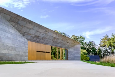Museum Peter August Böckstiegel Modernes, langes Gebäude mit Stein- und Glaselementen; eingebettet in grüne Landschaft unter blauem Himmel.