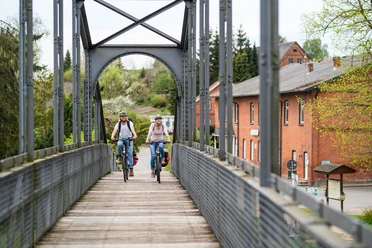 Zwei Fahrradfahrer fahren über die Brücke in Berkenthin. Sie überqueren den Elbe-Lübeck-Kanal.