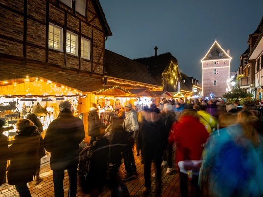 Der Monheimer Weihnachtsmarkt in der Altstadt mit Blick auf den Schelmenturm Ein belebter Weihnachtsmarkt in Monheims Altstadt, festliche Lichter und der historische Schelmenturm.