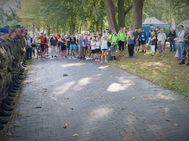 Volkslauf-Tag-der-Reservisten-Bad-Zwischenahn2.jpg Teilnehmer des Volkslaufes in Bad Zwischenahn, flankiert von Reservisten, versammelt auf einer Allee.