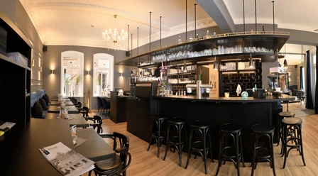 KÜPERs Bistro und Kaffeerösterei Ein großzügiger, stilvoll eingerichteter Bistro-Raum mit dunklem Mobiliar und Kronleuchter.