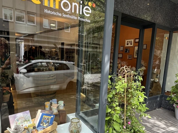 Senfonie 5.jpg Schaufenster mit Produkten der historischen Senfmühle Monschau. Vor dem Geschäft stehen dekorative Pflanzen.