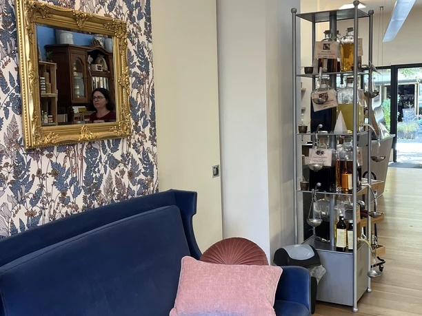 Senfonie 6.jpg Innenraum eines Geschäfts mit blauem Sofa und Regalen. Ein Spiegel reflektiert den Raum.