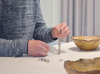 A man stacks small screw nuts on top of each other. mSa Team-Bash