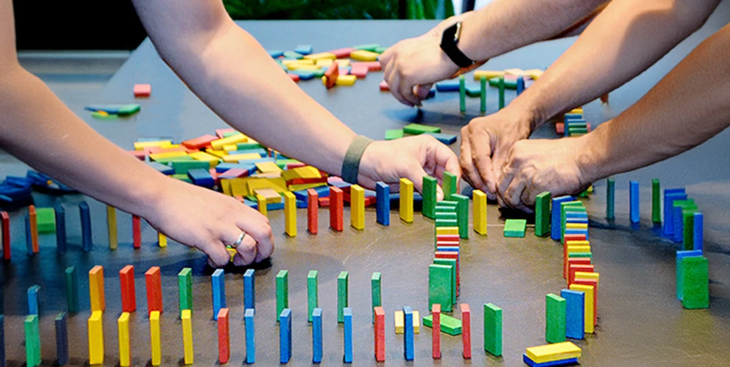 Three people are setting up a game of dominoes. mSa Team-Bash