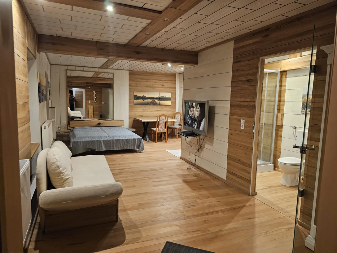 IMG-20240411-WA0000.jpg Wohnraum mit Holzakzenten, Schlafbereich, Sitzecke, Esstisch und angrenzendem Badezimmer.