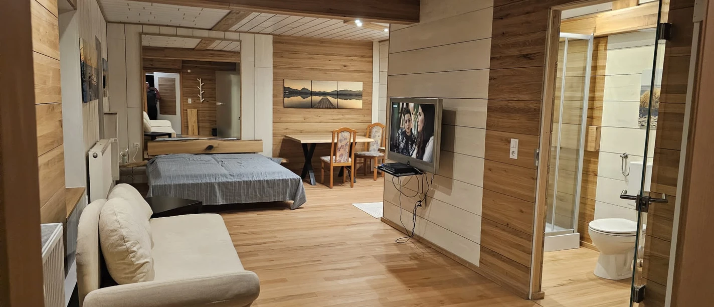 IMG-20240411-WA0000.jpg Wohnraum mit Holzakzenten, Schlafbereich, Sitzecke, Esstisch und angrenzendem Badezimmer.