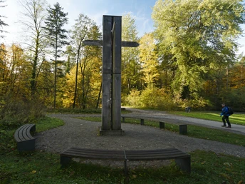 Externsteine_6©LTM GmbH, F. Grawe.JPG Holzkreuz auf einer kreisförmigen Plattform; umgeben von Bänken und Herbstlaub im Wald.