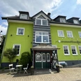 Haus Thal - Außenansicht Hotel in leuchtend grünem Gebäude mit Fachwerkdetails, Tischen und Stühlen im Freien, unter blauem Himmel.