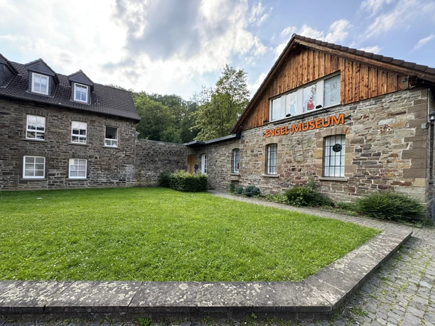 Engel-Museum Rasenfläche vor einem Gebäude mit Fachwerk und Steinmauer; darauf steht "Engel-Museum".