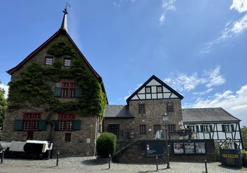 Bergisches Museum für Bergbau, Handwerk und Gewerbe Fachwerkhaus mit rotem Fensterrahmen, Efeu bewachsenen Wänden, Museumsschild, Kopfsteinpflaster.