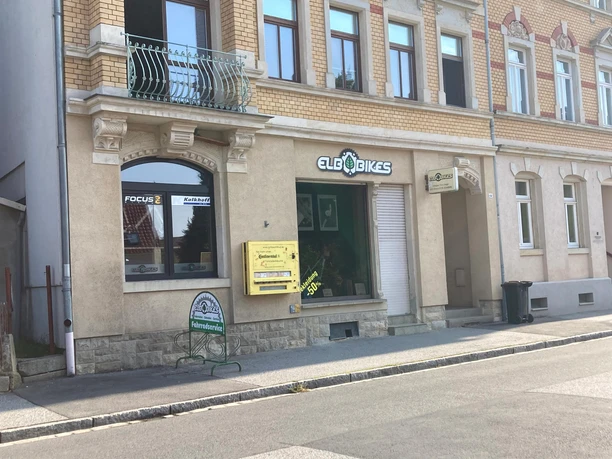 Elbbikes Fahrradladen in Pirna Fahrradgeschäft "ElbBikes" in einem historischen Gebäude mit gelbem Automaten und Werbeschild für Fahrradservice vor dem Schaufenster.