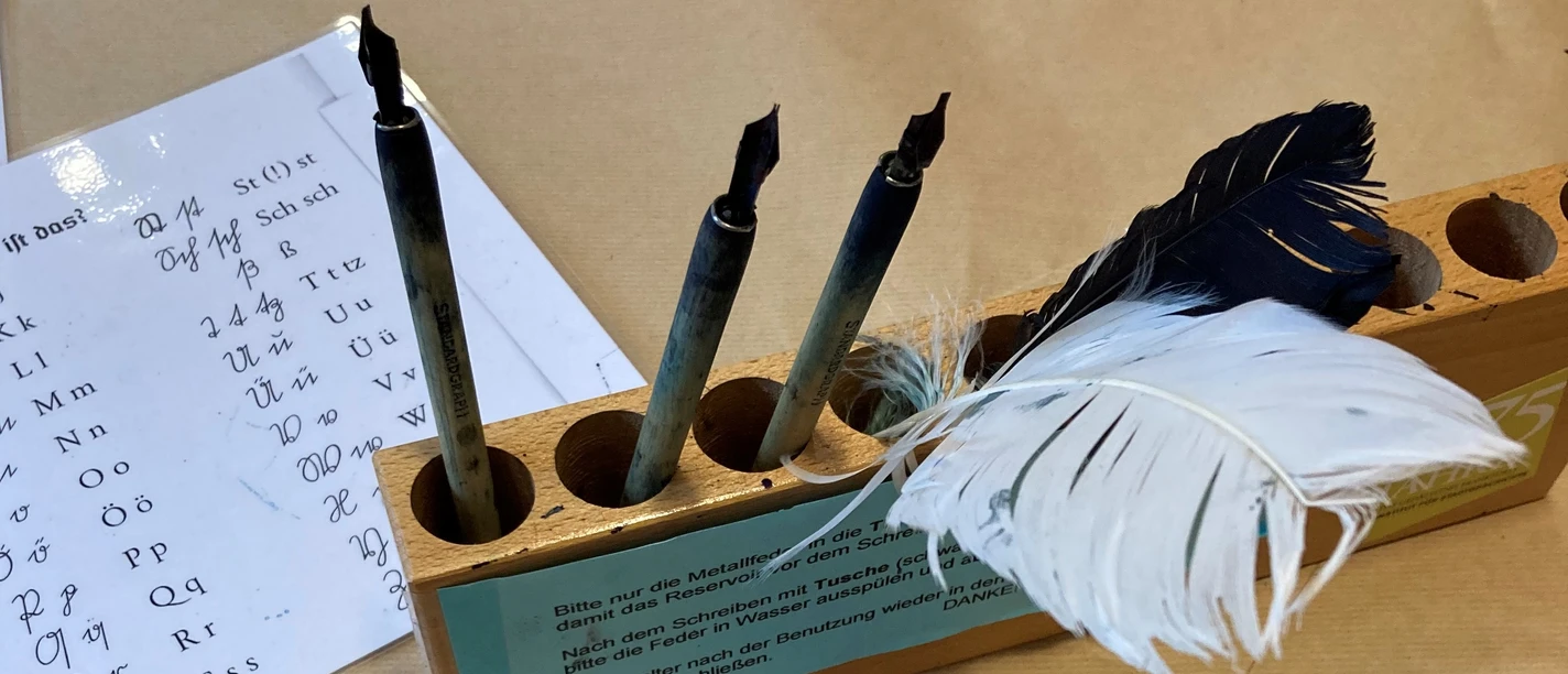 Schreibstation mit Federkielen und Tinte im Museum