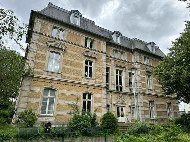 Kunstmuseum Villa Zanders Historisches dreistöckiges Gebäude mit gelben Ziegeln und dekorativen Fenstern, umgeben von Bäumen.