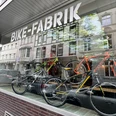 Bike-Fabrik Fahrradgeschäft mit modernen Bikes im Schaufenster und Spiegelung von Altbauarchitektur.