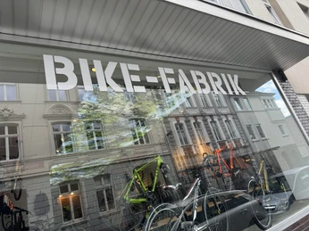 Bike-Fabrik Fahrradgeschäft mit modernen Bikes im Schaufenster, reflektierende Altbaufassaden im Glas.